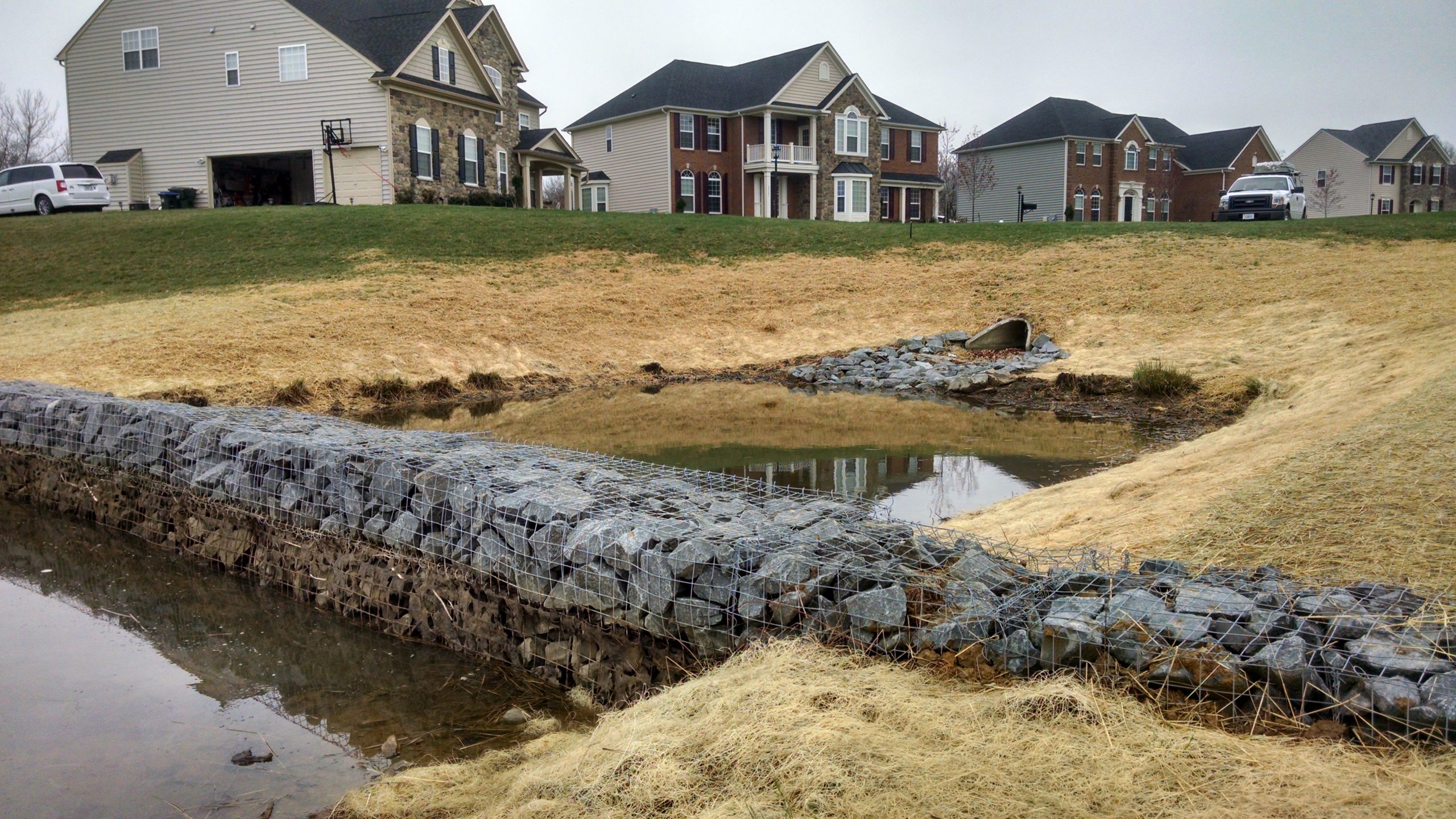 stormwater pond inlet with homes in the foreground
