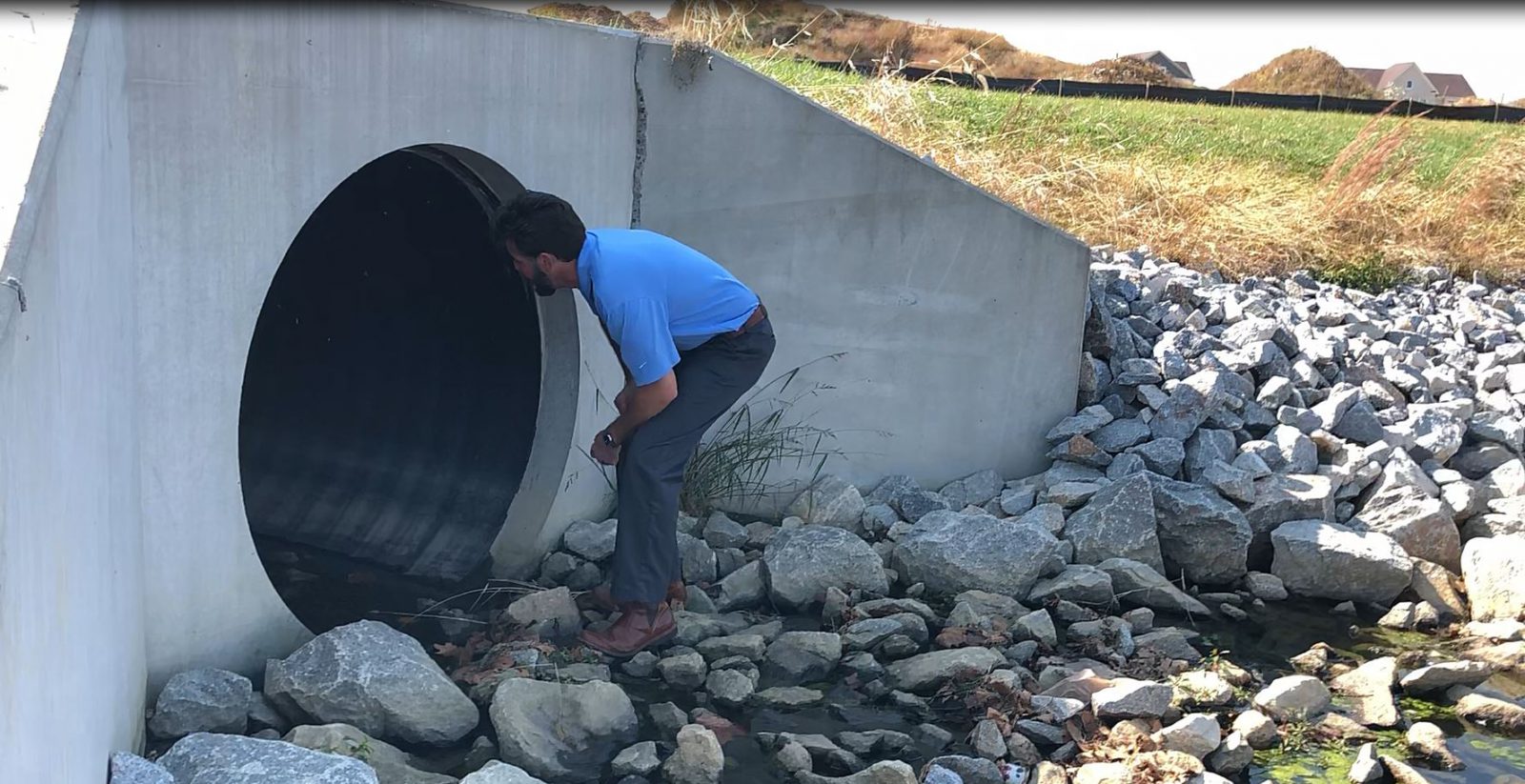 Professional inspecting large stormwater pipe structure for maintenance