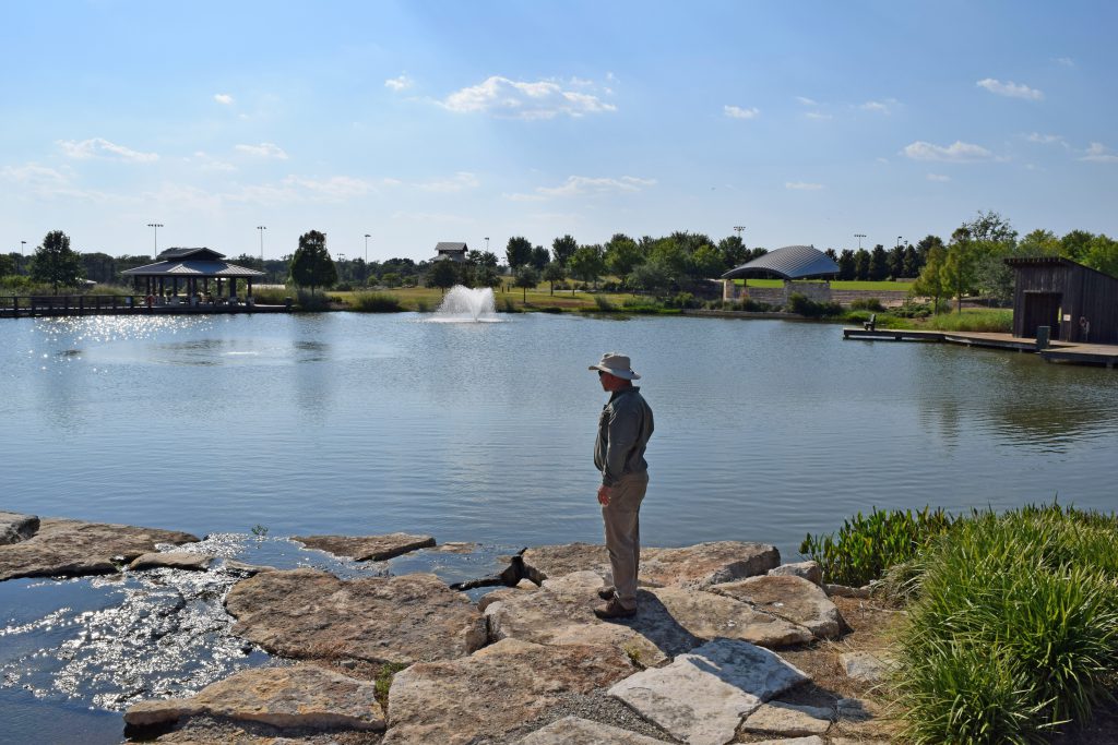 scenic lake and pond management guy staring at lake - Stay Ahead of Water Quality Issues with Annual Management - aib 2021