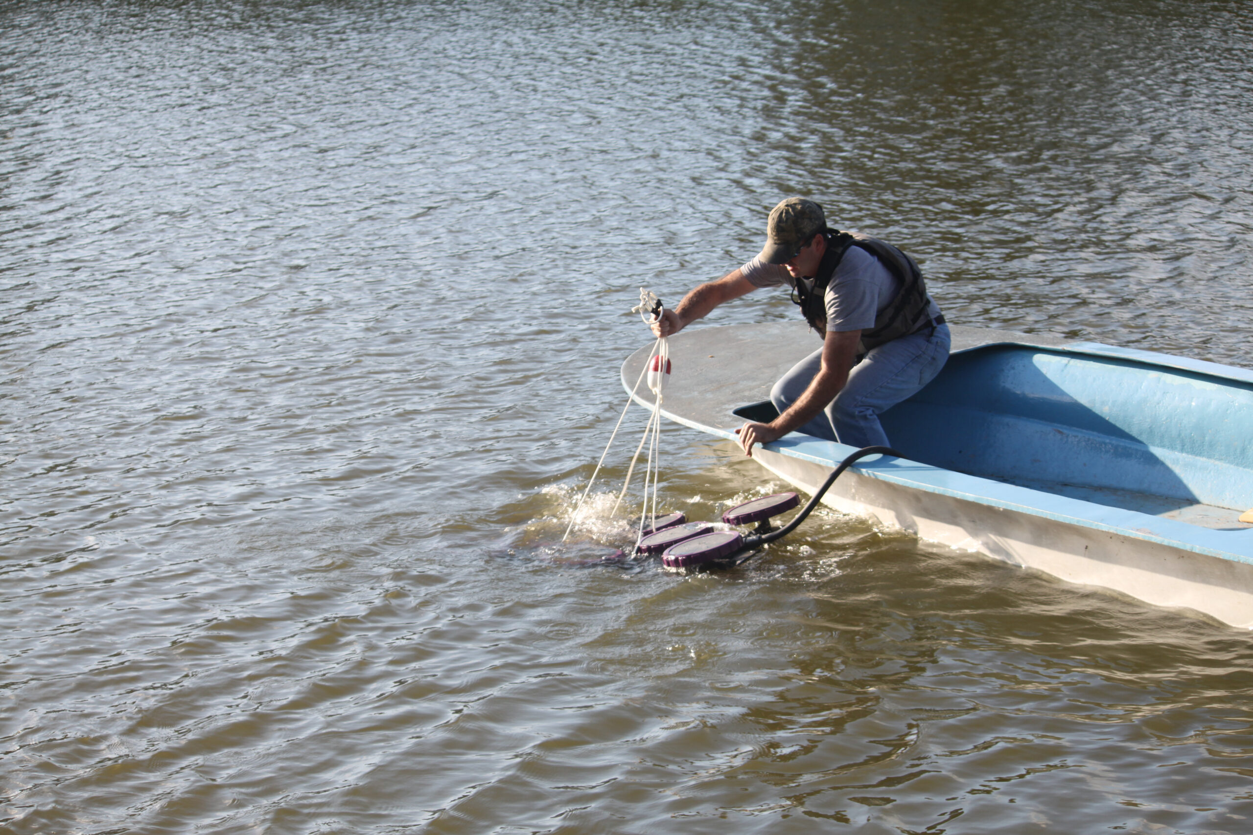 Technician deploying equipment from a boat to monitor water quality