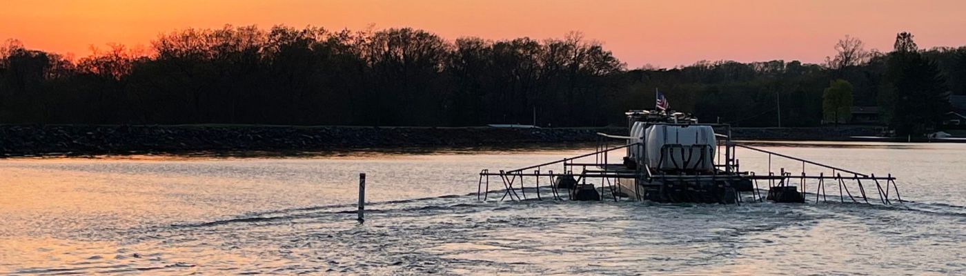 alum barge applying alum treatment to large lake at sunset