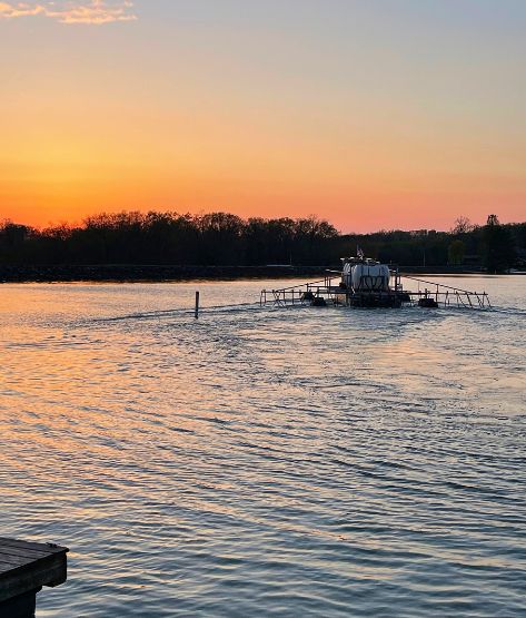 alum barge applying treatment out on a lake at sunset