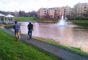 Lake management expert walking along community lake pathway with fountain