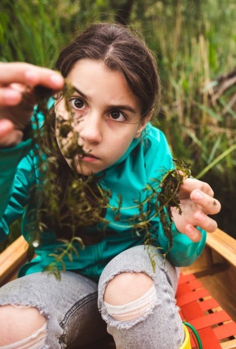 girl who is examining aquatic weeds from pond