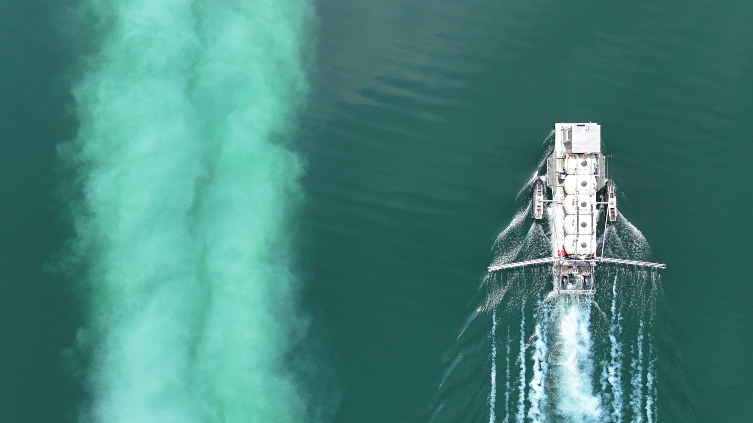 large-barge-in-water-applying-alum-white-trail-in-water