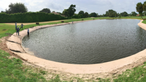 people installing a bioengineered living shoreline along the edge of a pond to repair erosion damage