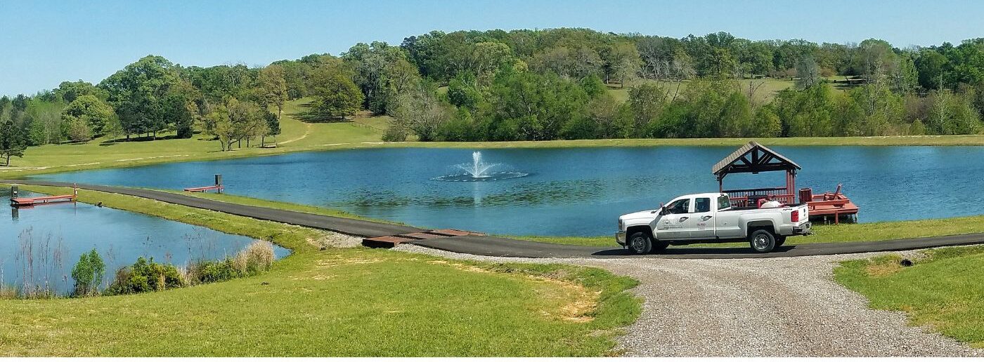 solitude lake management aquatic technician truck arriving to a lake with a fountain to perform routine maintenance