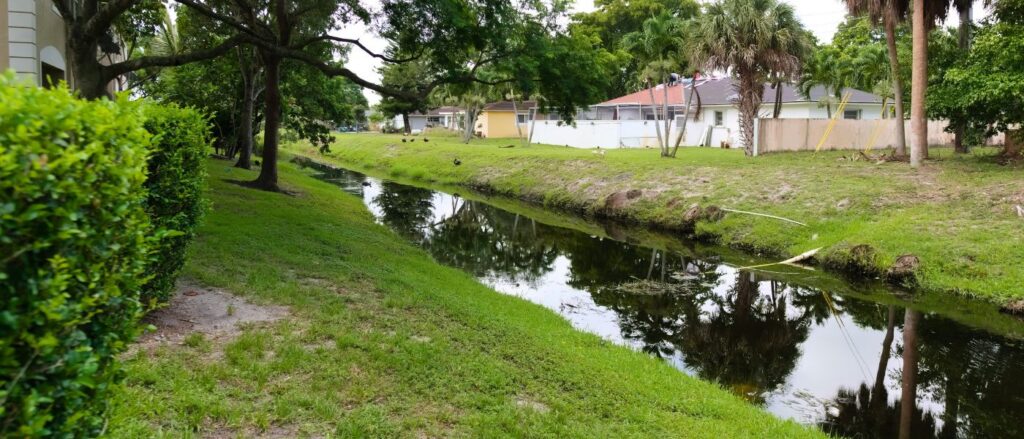 waterway behind residential community with eroding shorelines and exposed pipes