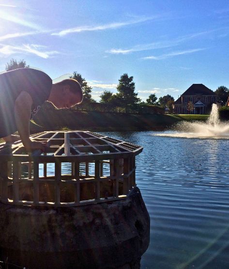 SOLitude aquatic expert inspecting a stormwater facility in a community pond with a fountain